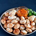 Kuzhi Paniyarams arranged in a plate with garlic chutney and coriander leaves