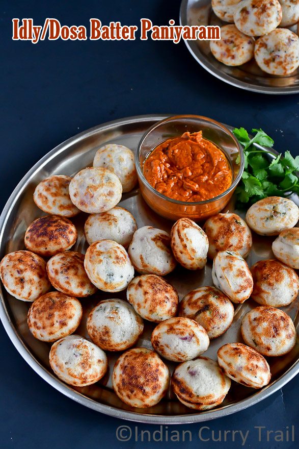 top view of kuzhi paniyarams arranged in a wide plate with chutney and coriander leaves aside