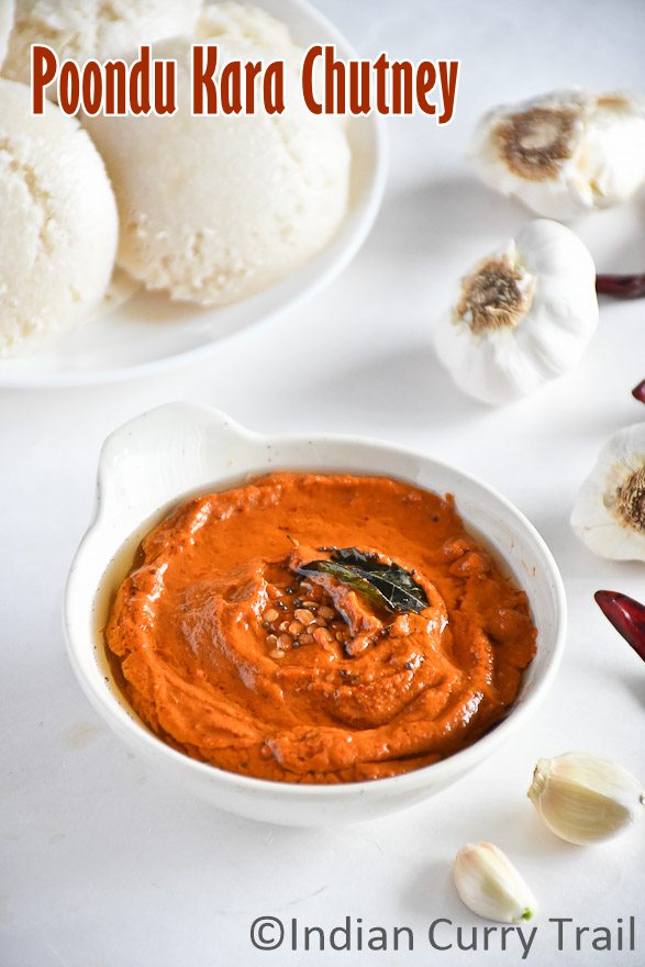 Spicy garlic chutney in a bowl topped with seasoning, curry leaves and Idlies kept behind