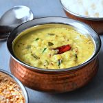 Closeup shot of Zucchini Kootu served in a bowl with red chilli on top and rice on side