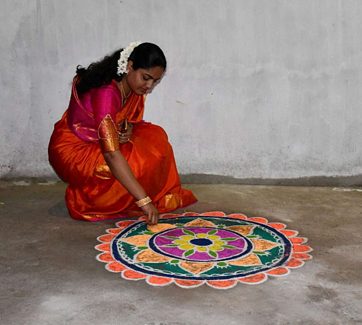 Uma Ramanujam-author of Indian Curry Trail in saree drawing a rangoli.