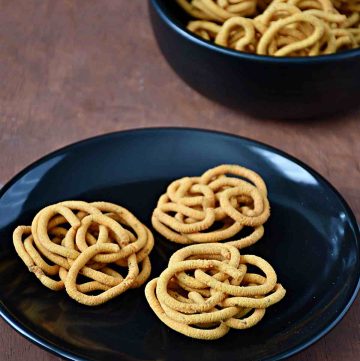 table view of besan murukku on a plate with bowl of murukkus behind