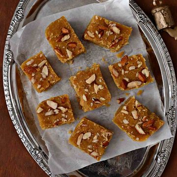 top view of toor dal burfi with nuts on top arranged on a plate