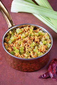 picture of celery paruppu usili with mustard seeds in a small serving bowl with dry red chilli and celery sticks aside