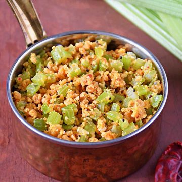 picture of celery paruppu usili with mustard seeds in a small serving bowl with dry red chilli and celery sticks aside