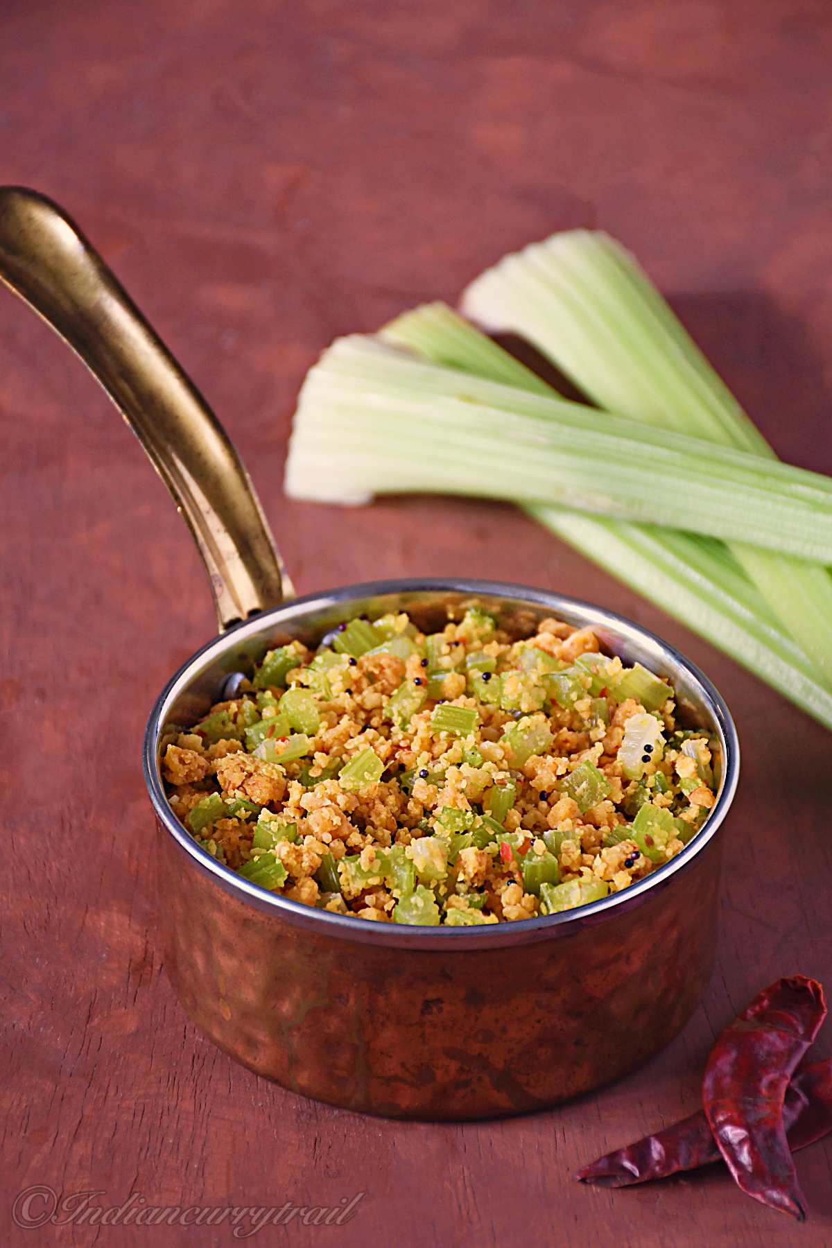 celery paruppu usili served in a copper bowl with mustard seeds and a hint of crushed dry red chillies