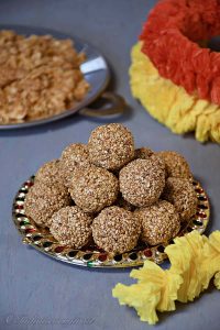 a decorative plate full of sesame laddus with garland nearby