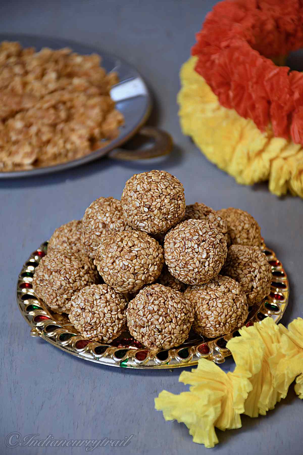 a decorative plate full of sesame laddus with garland nearby